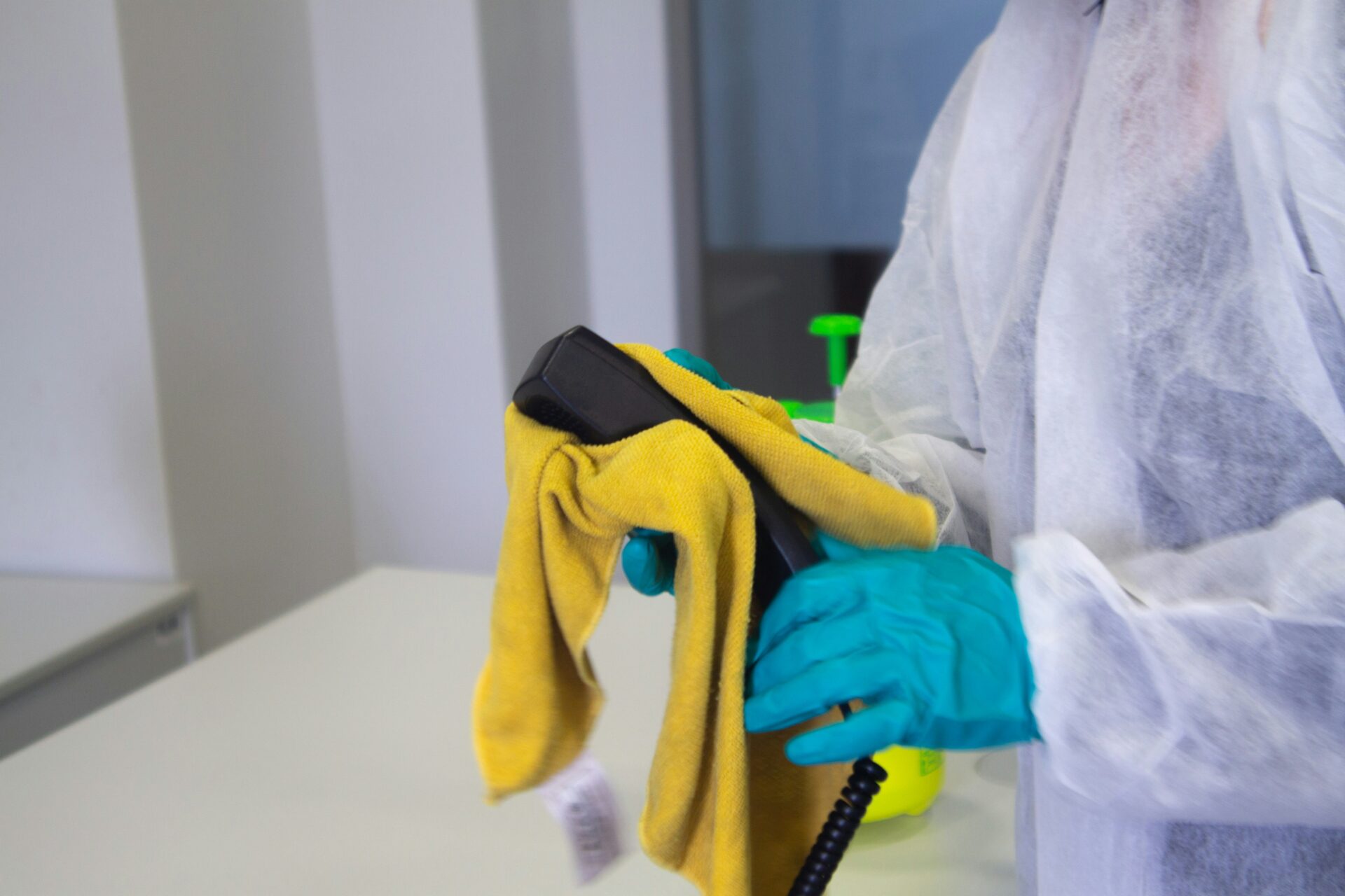 a person disinfects an office phone witha yellow cloth.